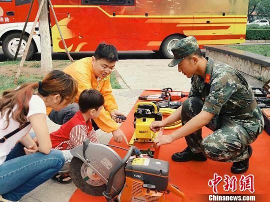 图为消防战士向一家三口讲解消防知识和消防器材使用。　崔耀天 摄